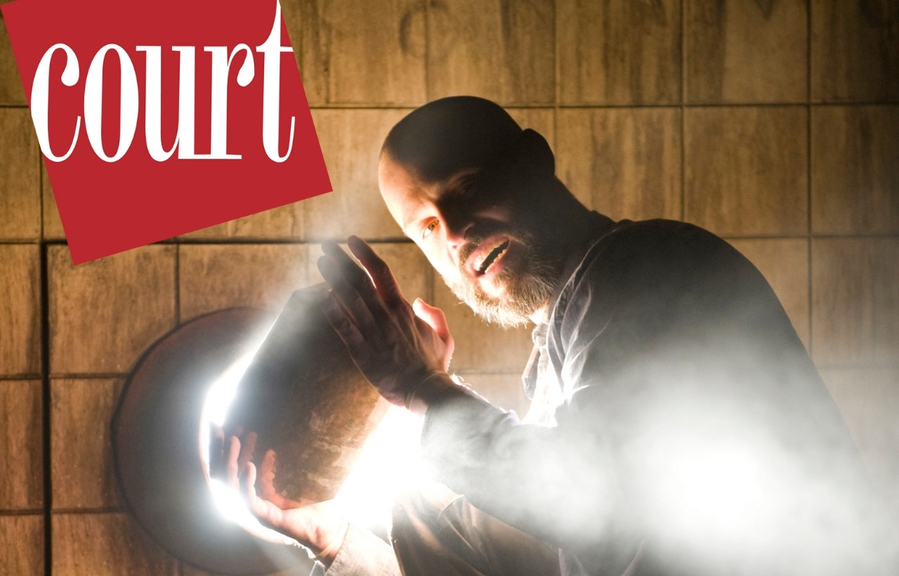 A man holds a stone over a light source; light spills out around him.
